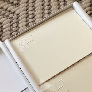 May include: A white box with a stack of ivory note cards. The top card has the initials "AH" embossed in a simple font.