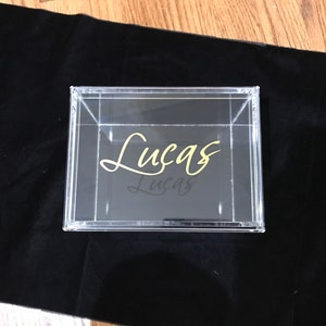 May include: A clear acrylic box with a gold inscription that reads "Lucas".