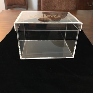 May include: A clear acrylic box with a lid. The lid has the name "Lucas" written in gold lettering.