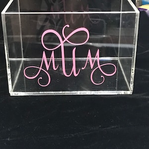 May include: A clear acrylic box with the word "Mum" written in pink cursive lettering.