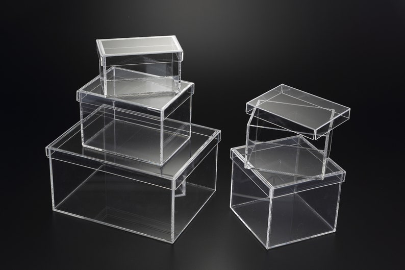 May include: Four clear acrylic boxes of varying sizes stacked on top of each other. The boxes are made of clear plastic and have a rectangular shape.