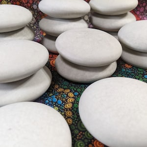 May include: A stack of smooth, white, round stones on a colorful patterned fabric background.