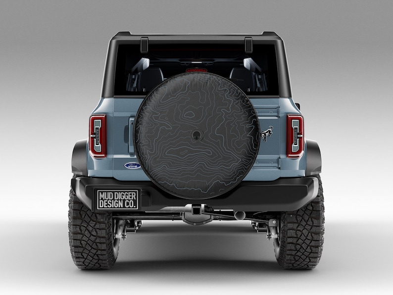 Custom Ford Bronco tire cover with backup camera port, designed for 2021-2025 models, weatherproof and UV-resistant. Perfect accessory for Ford Bronco owners, available in multiple colors and designs