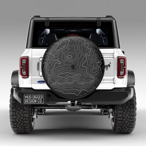Custom Ford Bronco tire cover with backup camera port, designed for 2021-2025 models, weatherproof and UV-resistant. Perfect accessory for Ford Bronco owners, available in multiple colors and designs