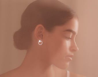 May include: A close-up of a person's ear with a small, silver hoop earring.
