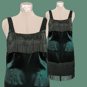 May include: A dark green sleeveless dress with a fringe trim around the neckline and hem.