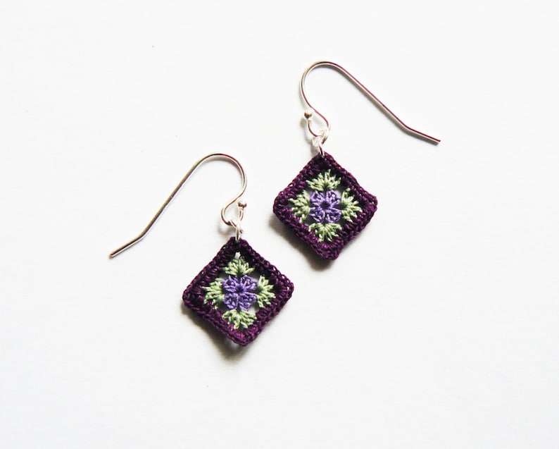 May include: A pair of purple crochet earrings with a green and purple flower design.