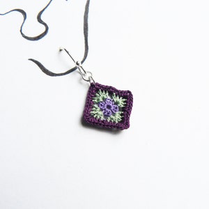 May include: Purple crochet earring with a green and purple flower design.