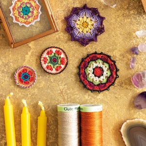 K&ouml;nnte beinhalten: Eine Sammlung von sechs bunten geh&auml;kelten Mandala-Designs mit einer Vielzahl von Farben, darunter Rot, Orange, Gelb, Gr&uuml;n, Blau und Lila. Die Mandalas sind auf einer braunen Oberfl&auml;che mit Garnrollen und anderen Dekorationsartikeln angeordnet.