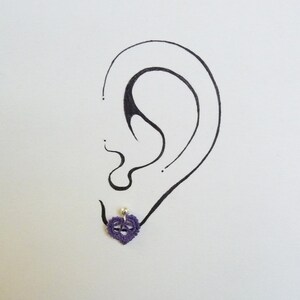 May include: A purple heart-shaped earring with a small pearl bead in the center.