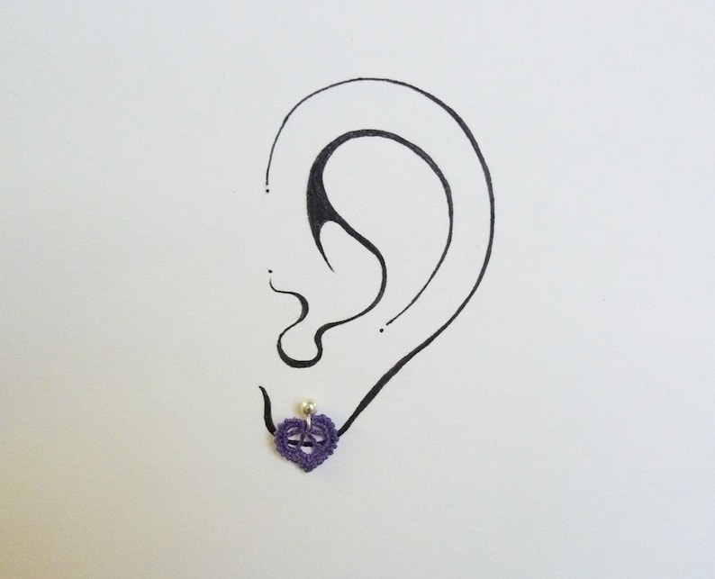 May include: A purple heart-shaped earring with a small pearl bead in the center.