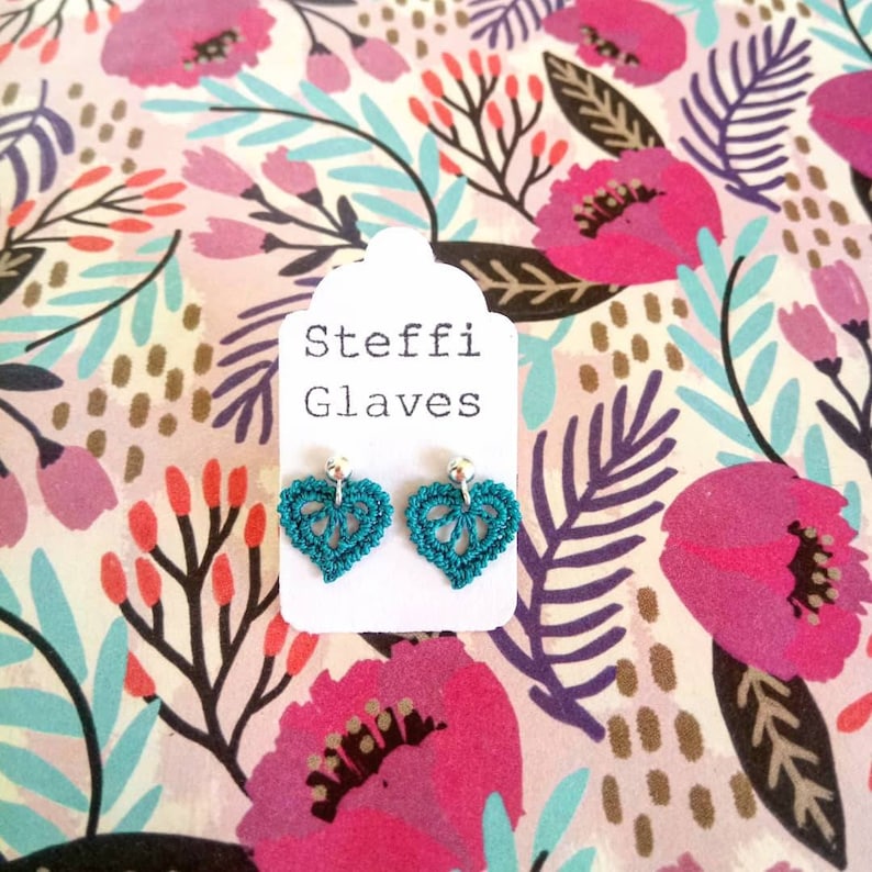May include: Teal crochet heart earrings with silver hooks on a white card with the text "Steffi Glaves".