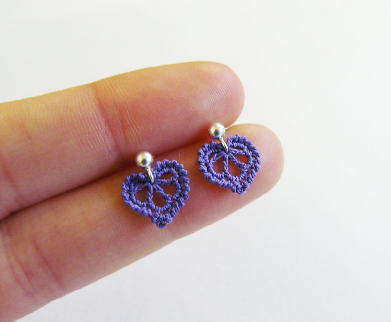 May include: A pair of purple crocheted heart-shaped earrings with silver posts.