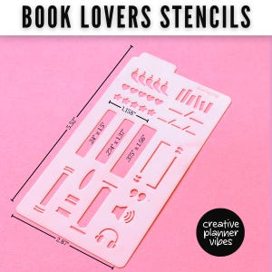 K&ouml;nnte beinhalten: Eine hellrosa Kunststoff-Schablonenplatte mit der Aufschrift BOOK LOVERS STENCILS und verschiedenen Ausstanzungen wie Herzen, Sternen und buchbezogenen Symbolen. Die Ma&szlig;e betragen 14,02 cm mal 7,29 cm, mit internen Ausstanzungen von 2,94 cm Breite.