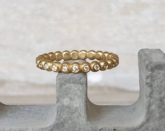 Può includere: Un anello a fascia d'oro con piccoli diamanti rotondi incastonati nella fascia.