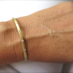 May include: A gold bangle bracelet with small diamonds set into the band.