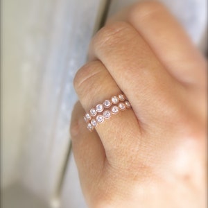 May include: A rose gold ring with two rows of bezel-set round diamonds.