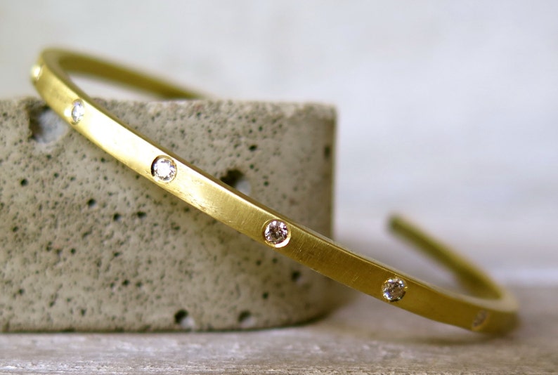 May include: A gold bangle bracelet with small diamonds set into the band.