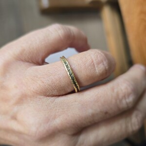 Pu&ograve; includere: Un anello a fascia d'oro con una fila di piccoli diamanti incastonati al centro.