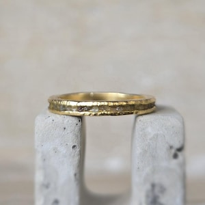 Pu&ograve; includere: Un sottile anello a fascia d'oro con una fila di piccoli diamanti incastonati nella fascia.