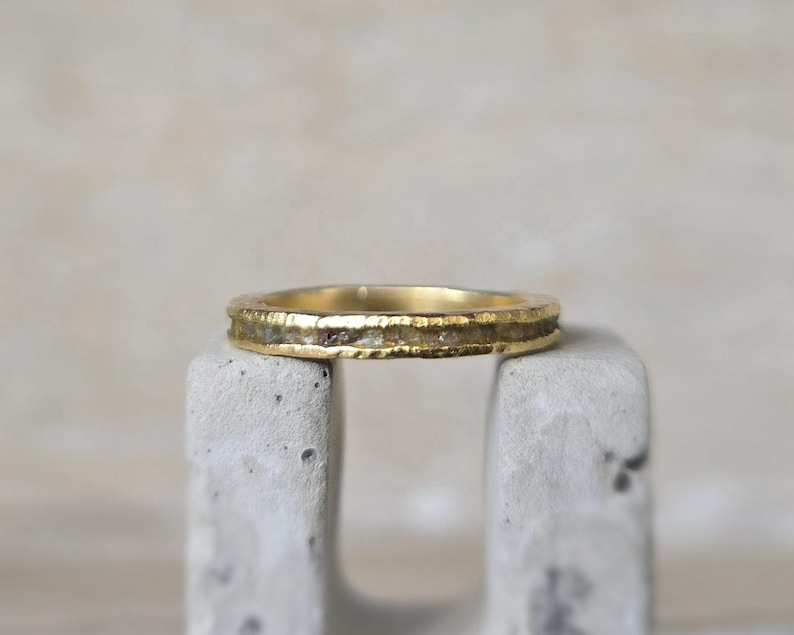Pu&ograve; includere: Un sottile anello a fascia d'oro con una fila di piccoli diamanti incastonati nella fascia.