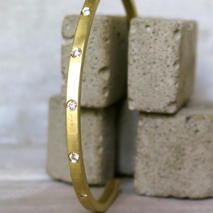May include: A gold bangle bracelet with small diamonds set into the band.