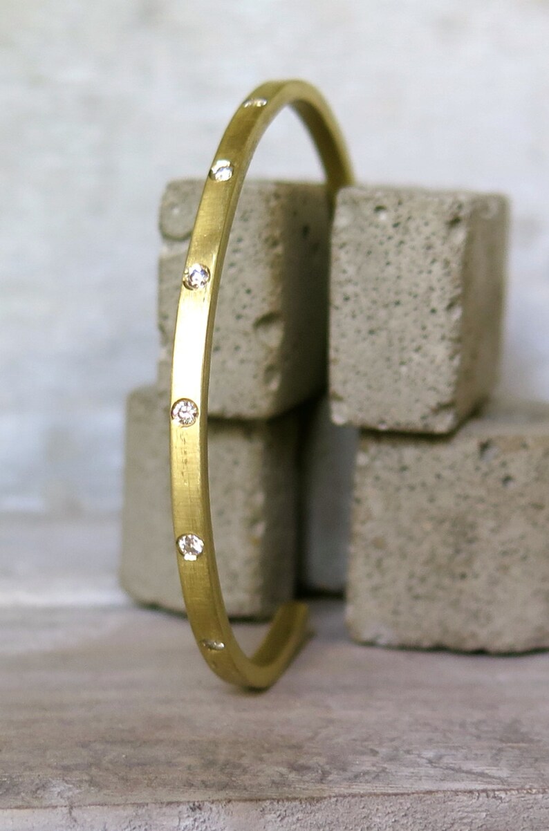 May include: A gold bangle bracelet with small diamonds set into the band.
