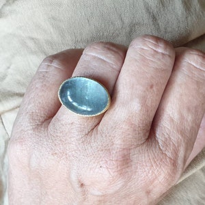 May include: A silver ring with a large oval-shaped blue gemstone set in a gold band.