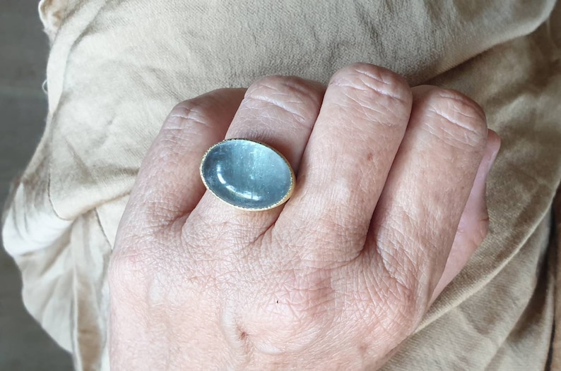 May include: A silver ring with a large oval-shaped blue gemstone set in a gold band.