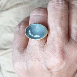 May include: A ring with a large oval-shaped blue gemstone set in a gold band.
