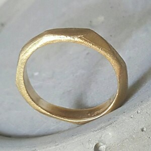 May include: A gold ring with a textured, irregular shape. The ring is thick and has a rounded edge.