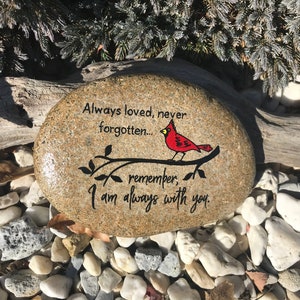 以下が含まれることがあります： 「Always loved, never forgotten... remember, I am always with you.」というテキストと、枝に描かれた赤いカージナルが描かれた、ペイントされた石です。
