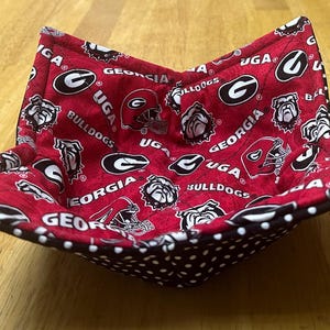 May include: A set of three ceramic mugs with a speckled, matte finish. The mugs are in shades of cream, light gray, and dark gray. Each mug has a simple, minimalist design and a rounded handle.