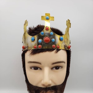 May include: A gold crown with red and blue gemstones on a mannequin head with a brown beard.