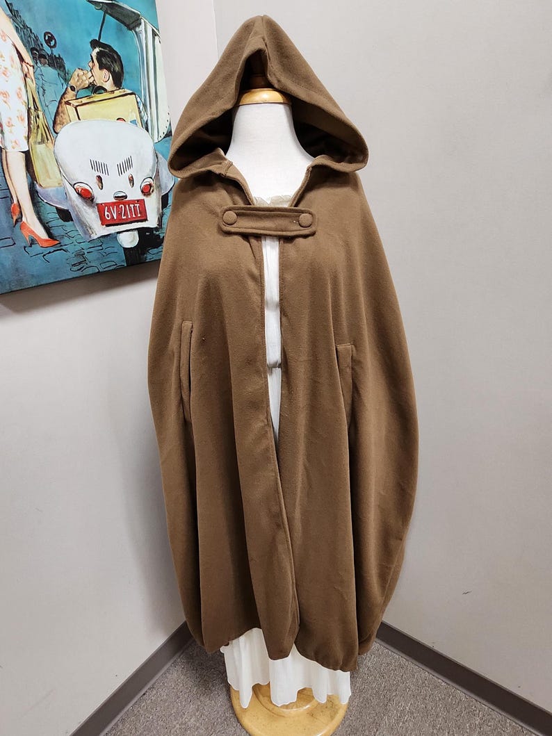 May include: A brown hooded cape with two buttons on the front. The cape is made of a soft, warm fabric and has a relaxed fit.