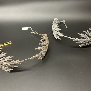 May include: Two silver and gold jeweled headbands with a delicate, branch-like design. The headbands are adorned with small, clear rhinestones.