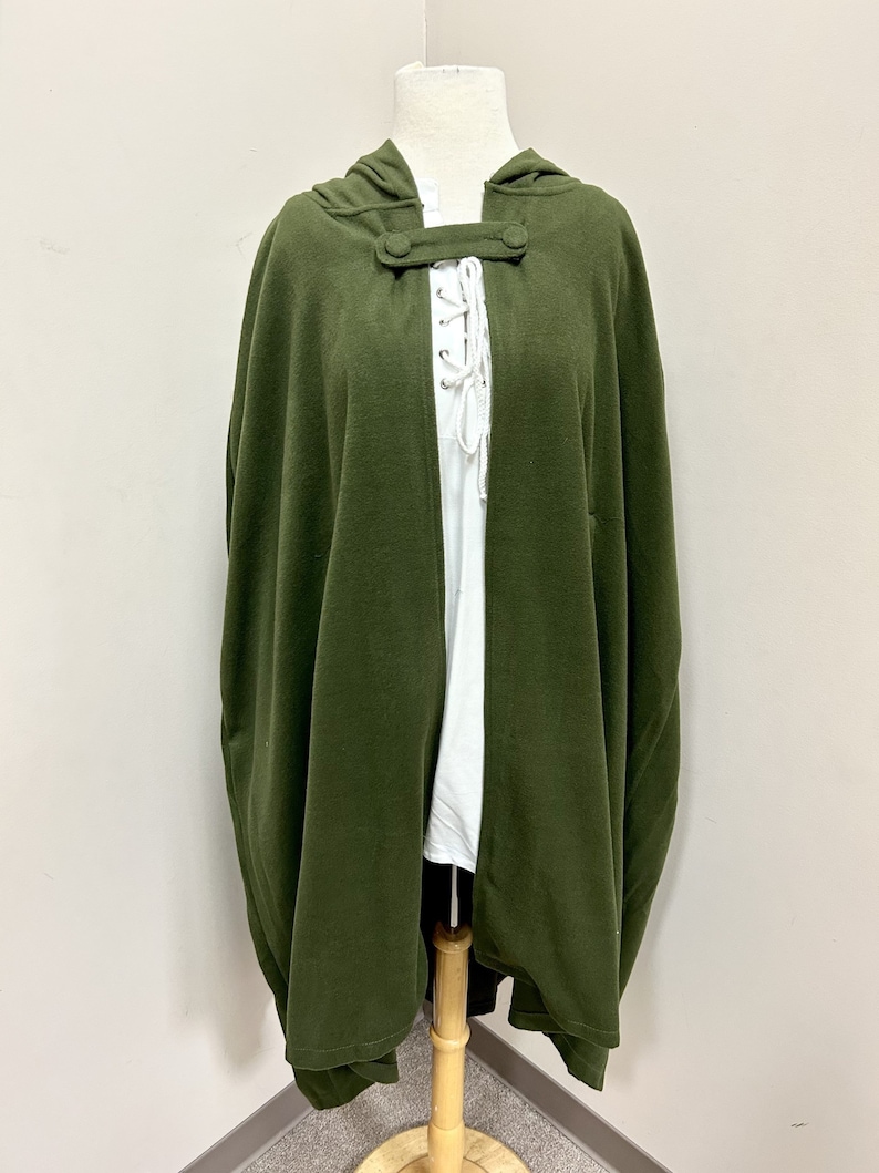 May include: A hooded green cape with a button and lace closure. The cape is made of a soft, comfortable fabric and has a relaxed fit.