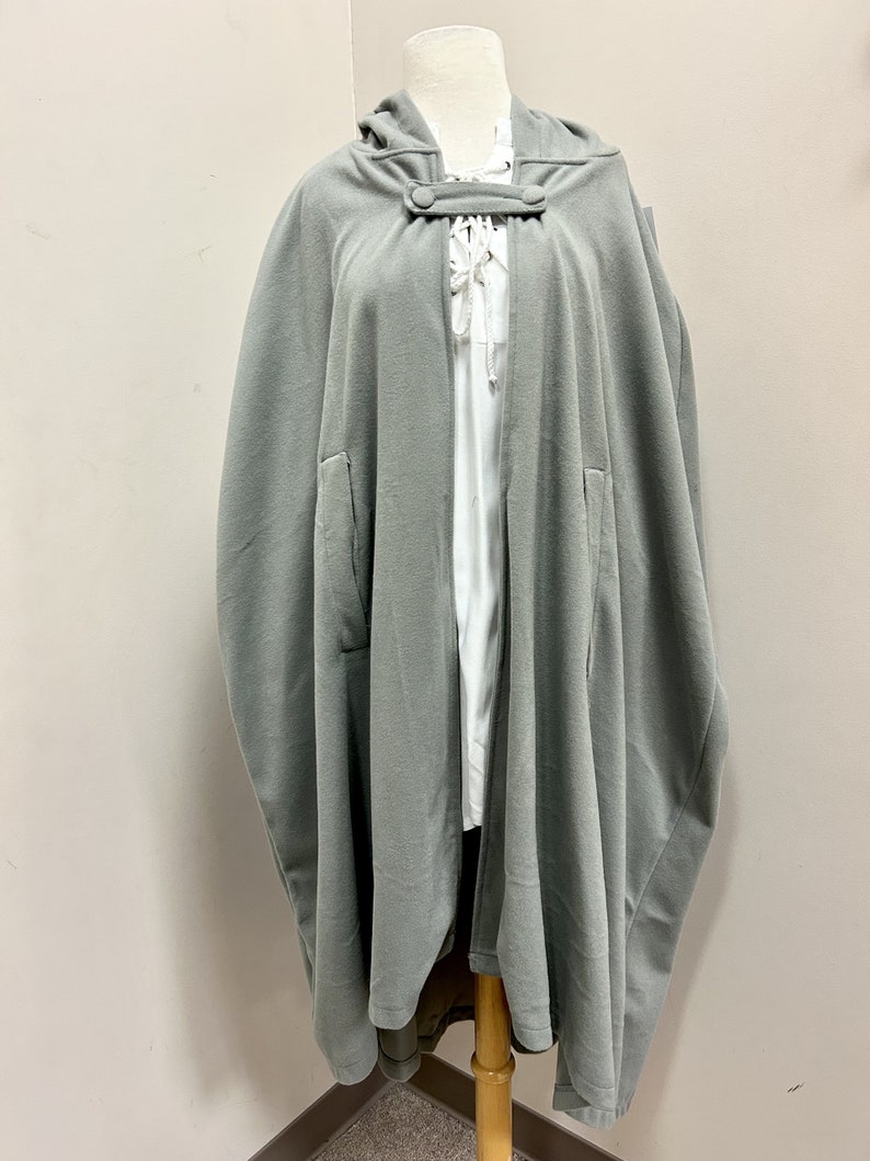 May include: A gray hooded cape with a button closure and a lace-up detail at the neck.