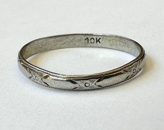 May include: A simple, silver band ring with a 10K stamp and a delicate, engraved design.