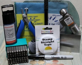 Könnte beinhalten: Ein Metall-Stempelset mit Werkzeugen und Zubehör für die Schmuckherstellung. Das Set enthält einen Hammer, einen Metallblock, einen Satz Buchstabenstempel, eine Rolle Klebeband, eine Flasche Emaille, eine Zange, ein Poliertuch, einen Sharpie-Marker und verschiedene Metallformen.