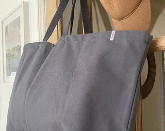 May include: A dark gray canvas tote bag with black handles. The bag has a small white label with the word "SCANDI" printed on it.