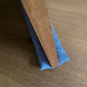 May include: A blue and white chevron patterned doorstop placed under a wooden door.