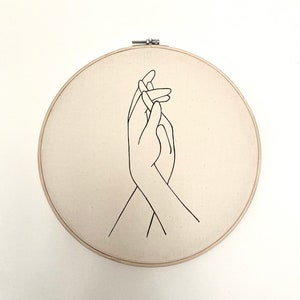 embroidery hoop with drawing of hands holding.