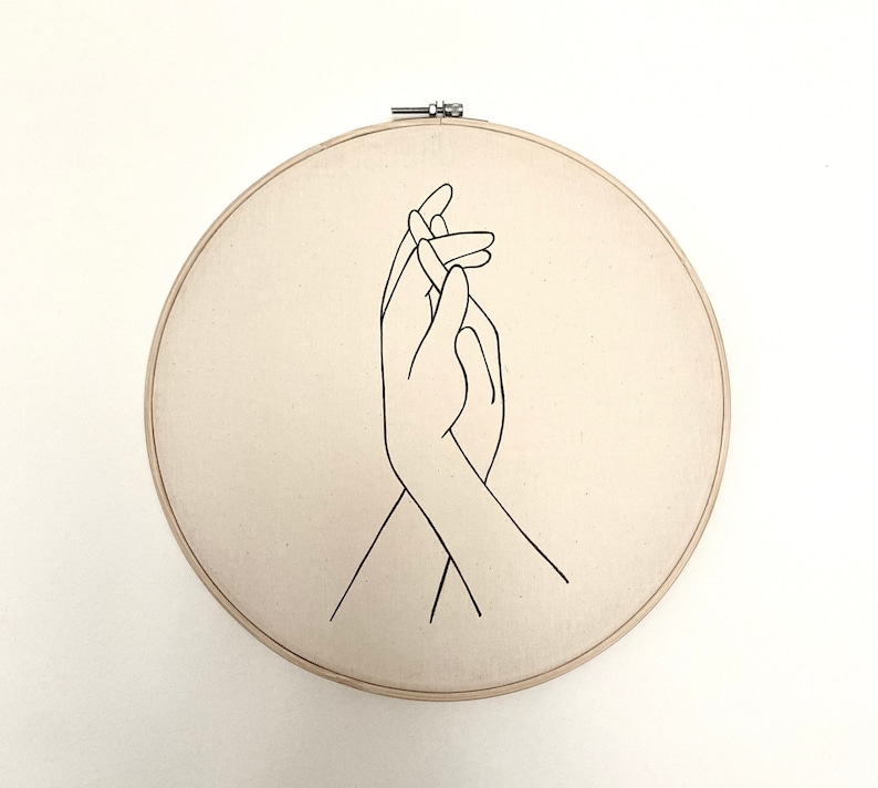 embroidery hoop with drawing of hands holding.