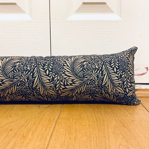 May include: A black and gold doorstop with a floral pattern. The doorstop is made of fabric and is filled with stuffing.