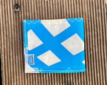 Könnte beinhalten: Ein quadratisches Portemonnaie aus einem strapazierfähigen, halbtransparenten Material mit einem hellblauen und weißen Rautenmuster. Das Portemonnaie hat sichtbare weiße Nähte an den Kanten und ein kleines rechteckiges Etikett mit dem Aufdruck cam.