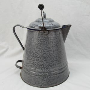May include: A vintage gray speckled enamelware coffee pot with a lid and handle. The pot has a spout for pouring and a small handle on the side. The lid has a black handle and a hinged mechanism.