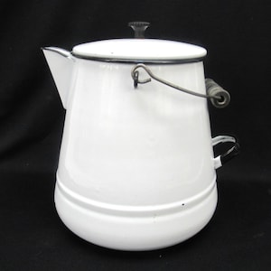 May include: White enamelware coffee pot with a black rim and handle. The pot has a lid with a black knob and a metal handle. The spout is on the left side. The pot is a classic design.