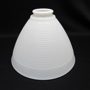 May include: White glass lampshade with a conical shape and a textured, dotted surface. The lampshade has a smooth, rounded rim at the base and a small, circular opening at the top. The lampshade is designed to diffuse light.