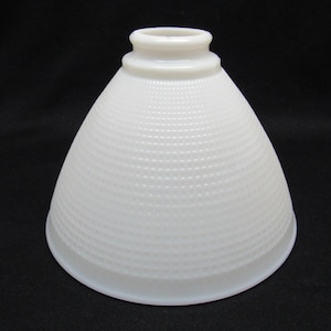 Puede incluir: Una pantalla de lámpara blanca en forma de cono con un patrón texturizado y punteado. La pantalla tiene una base redondeada y una parte superior cilíndrica más pequeña. La forma general recuerda a una campana. La pantalla está hecha de vidrio opaco.